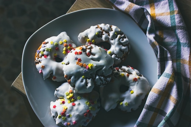 Foto ein teller mit süßigkeiten mit weißem zuckerguss, gelb-roten streuseln. hausgemachte donuts rosquillas traditionell