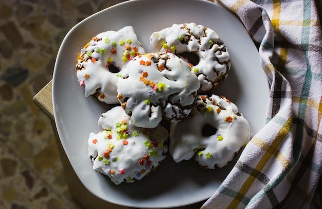 Foto ein teller mit süßigkeiten mit weißem zuckerguss, gelb-roten streuseln. hausgemachte donuts rosquillas traditionell