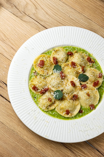 Ein Teller Ravioli mit grüner Soße und Parmesankäse