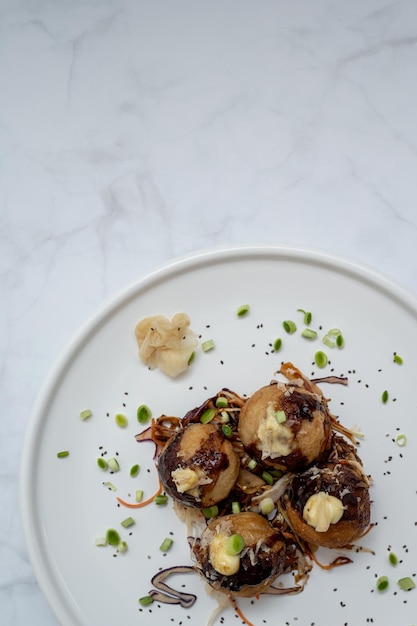 Ein Teller Takoyaki über einem Marmortisch