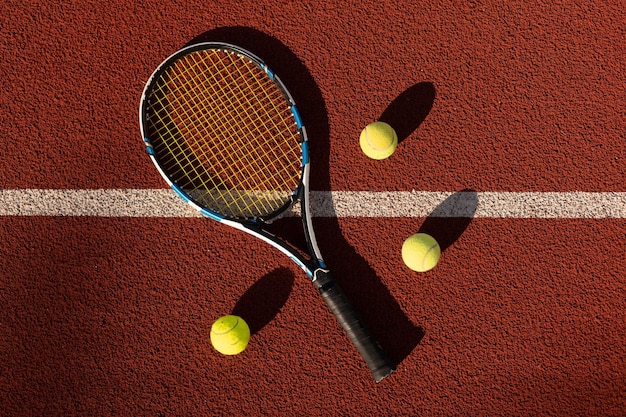 Ein Tennisschläger und ein neuer Tennisball auf einem frisch gestrichenen Tennisplatz.