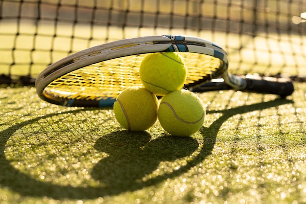 Ein Tennisschläger und ein neuer Tennisball auf einem frisch gestrichenen Tennisplatz.