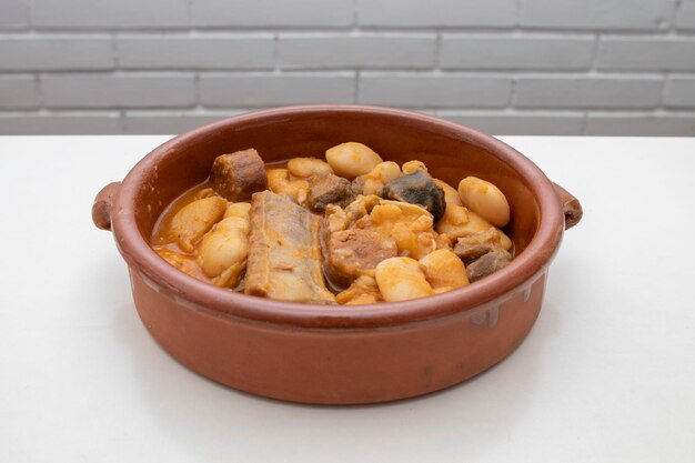 Foto ein terrakotta-teller mit asturischer fabada, einem typisch spanischen bohneneintopf auf weißem hintergrund