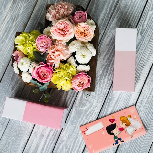 Ein Tisch, auf dem ein Korb mit Rosen und Blumen liegt, daneben Schachteln und ein Umschlag