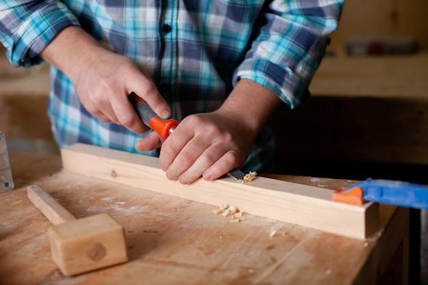 Ein Tischler im karierten Hemd arbeitet in einer Werkstatt. Holz. Ökologische Verträglichkeit. Lebensstil. Nahaufnahme Foto in hoher Qualität