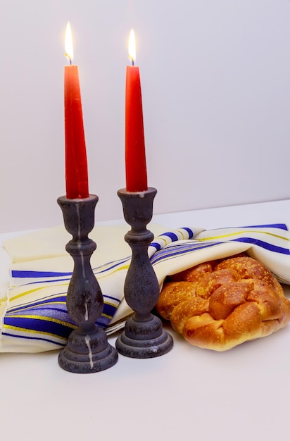 Ein Tischset für Schabbat mit brennenden Kerzen, Challah-Brot und Wein