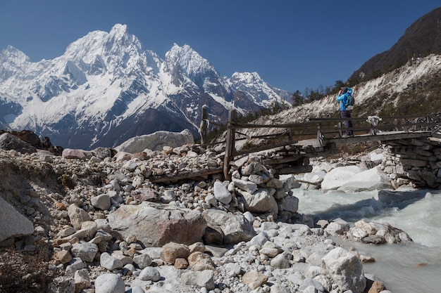 Ein Tourist, der auf der Brücke steht, fotografiert die schneebedeckten Berge. Himalaya, Bimtang