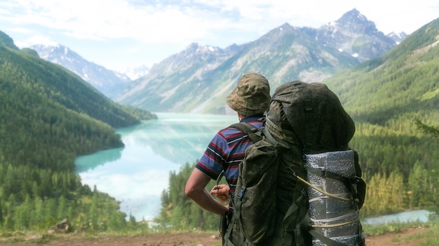 Ein Tourist mit einem riesigen Rucksack schaut auf den See.