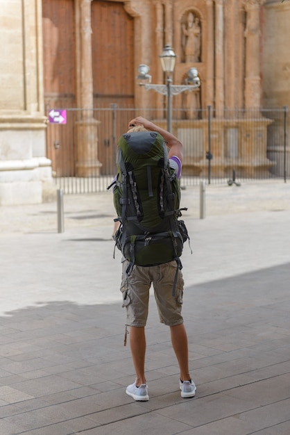 Ein Tourist mit einem Rucksack auf der Straße fotografiert die Rückansicht der Kathedrale