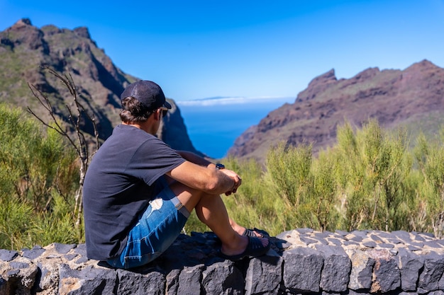 Ein Tourist mit Mütze blickt auf die Berggemeinde Masca im Norden der Kanarischen Inseln Teneriffa