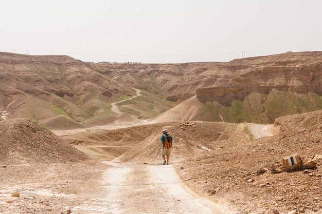 Ein Tourist mit Stöcken geht auf einer Sandstraße durch die Judäische Wüste