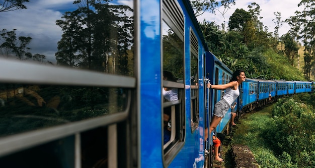 Ein Tourist reist mit dem Zug zu schönen Orten, einem Panorama. Eine schöne Frau reist mit dem Zug um die Welt. Reisen Sie mit dem Zug in Sri Lanka. Ein Reisender in Sri Lanka. Eisenbahnverkehr. Platz kopieren