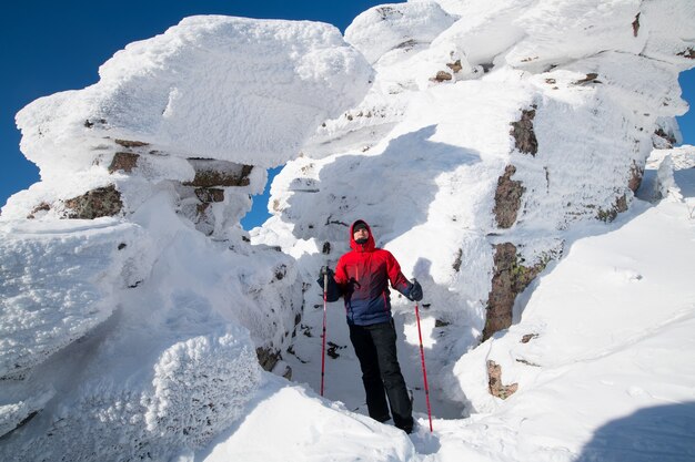 Ein Tourist steht auf einem Berg in einem schneebedeckten polaren Winter bei sonnigem Wetter