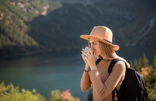 Ein Touristenmädchen ruht sich nach einem harten Aufstieg auf den Berg aus. Eine Reisende trinkt heißen Tee in den Bergen.