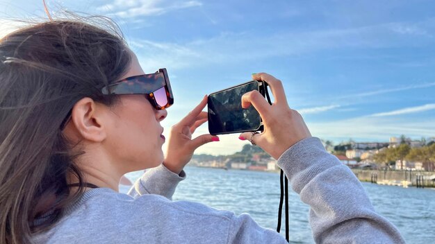 Ein touristisches Mädchen, das einen See mit ihrem Handy fotografiert Ansicht eines touristischen Mädchens, das Fotos mit ihrem Handy macht
