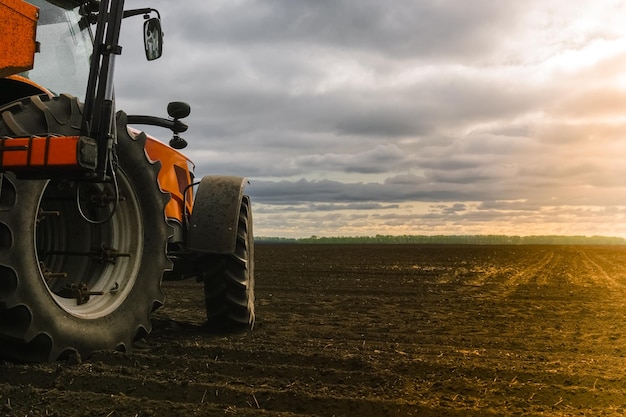 Ein Traktor auf dem Feld auf dem Hintergrund von unbebauten Flächen Kopieren Sie Platz