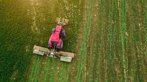 Ein Traktor mäht mit einer Drohne ein Luftbildfeld