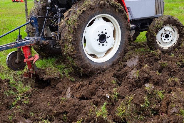 Ein Traktor mit einem Pflug pflügt im Frühjahr ein landwirtschaftliches Feld zum Anpflanzen von Kartoffeln. Das Land pflügen, Nahaufnahme.