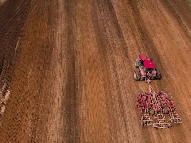 Ein Traktor mit einer Scheibenegge pflügt ein Feld für die Aussaat Luftaufnahmen