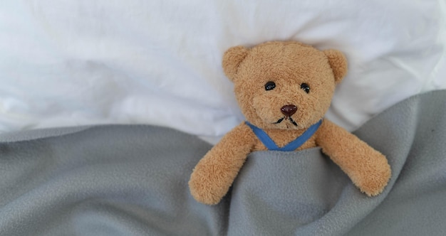 Ein trauriger Teddybär liegt vor Enttäuschung und Entmutigung krank im Bett