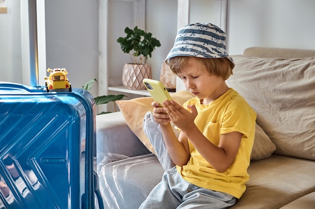 Ein trauriges Kind sitzt mit einem Handy auf einem Sofa und wartet auf den Umzug der Familie fl