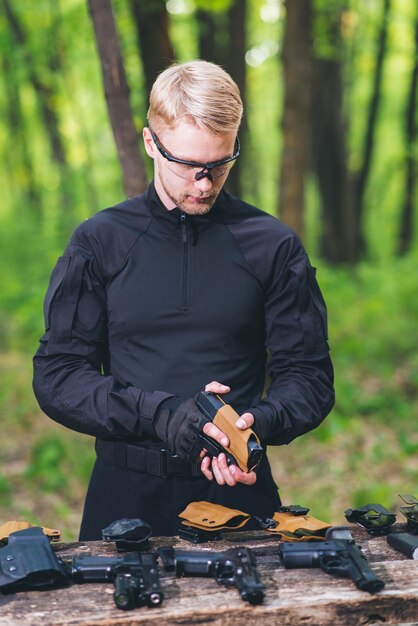 Ein Typ im Wald testet seine Waffen für Schießsport.