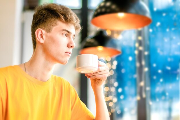 Ein Typ mit Tasse in der Hand, der nachdenklich durch das Fenster schaut