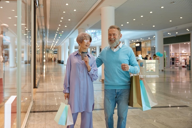 Ein überglücktes Seniorenpaar mit Einkaufstaschen freut sich über erfolgreiche Einkäufe