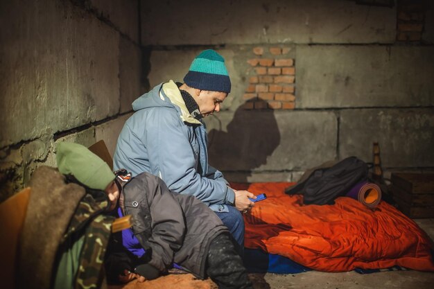 Foto ein ukrainischer vater mit kindern sitzt in einem bombenunterkunft und liest die neuesten nachrichten über die russischen eindringlinge