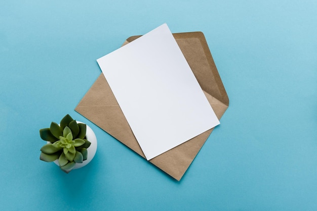 Ein Umschlag aus Kraftpapier und eine weiße leere Postkarte auf blauem Hintergrund Postkartenvorbereitung