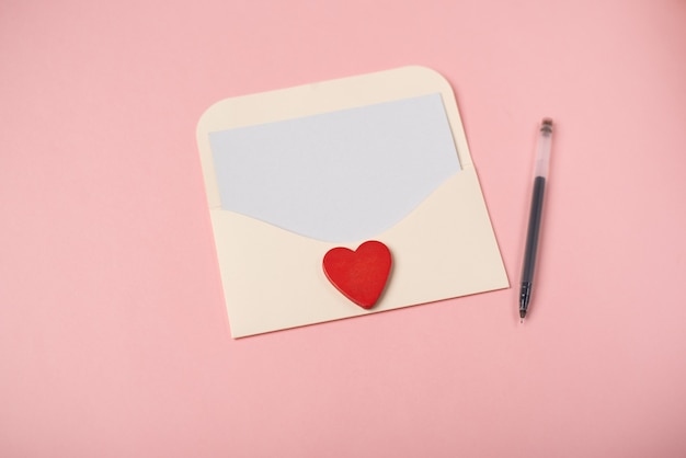 Ein Umschlag mit einem leeren Blatt Papier innen mit rotem Holzherz. Das Konzept des Valentinstags.