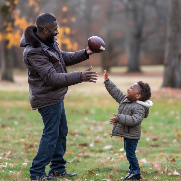 Ein Vater in einer Winterjacke überreicht seinem aufgeregten jungen Sohn in einem blattüberzogenen Park einen Fußball