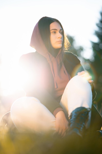 Ein verärgerter Teenager, der allein im Park sitzt, während die Sonne hinter ihr untergeht