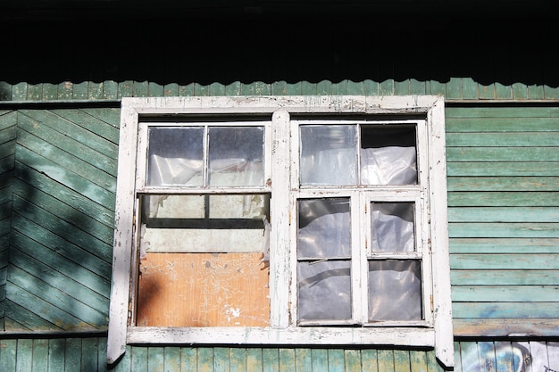 Ein verfallenes verlassenes Holzhaus. Altes Gebäude. Unbewohntes Haus. Ein vernageltes Fenster und niemand da. Eine zerbrochene Fensternahaufnahme.