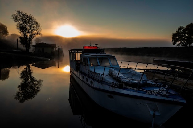 Ein Vergnügungsboot, das am frühen Morgen am Pier im Fluss festgemacht ist