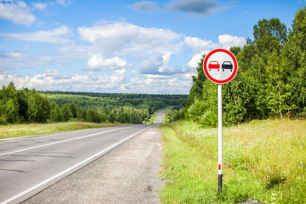 Foto ein verkehrsschild überholen ist an einem sonnigen sommertag auf einer vorstadtautobahn durch den wald verboten.