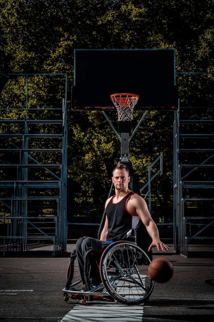 Ein verkrüppelter Basketballspieler im Rollstuhl spielt auf einem offenen Spielfeld.