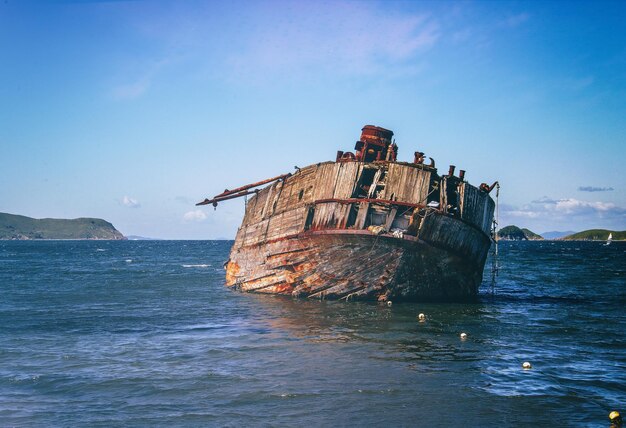 Foto ein verlassenes boot im meer gegen den blauen himmel