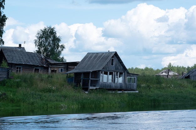 ein verlassenes Dorf am Flussufer, verlassene Holzhäuser mit leeren Fenstern