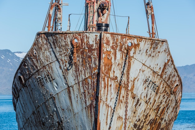 Foto ein verlassenes, rostiges schiff, das auf dem meer gegen den himmel verankert ist.