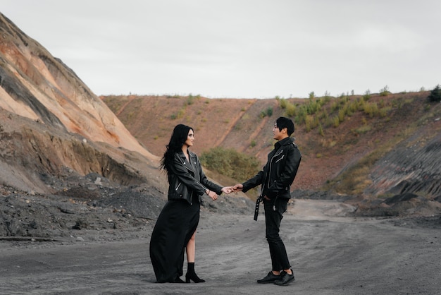 Ein verliebtes asiatisches Paar in schwarzer Lederkleidung geht in der Natur zwischen den Bäumen spazieren. Stil, Mode, Liebe.