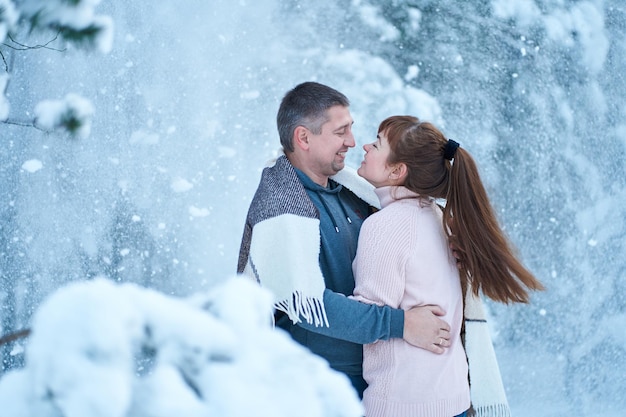Ein verliebtes Paar, das sich beim Spaziergang durch einen märchenhaft verschneiten Winterwald küsst