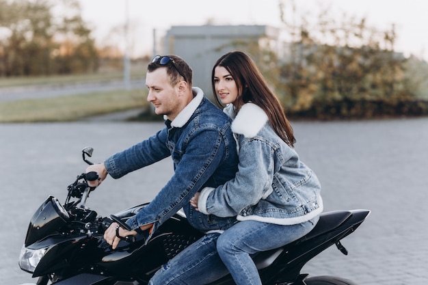 Ein verliebtes Paar, ein Mann und ein Mädchen, die beim ersten Date ein schwarzes Sportmotorrad fahren