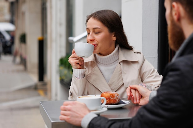 Ein verliebtes Paar frühstückt mit Kaffee und einem Donut in einem Café im Freien