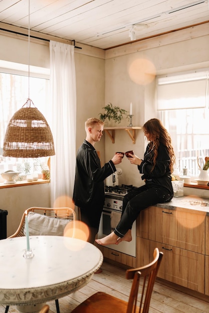Ein verliebtes Paar frühstückt und trinkt Tee in einer dekorierten Küche im Öko-Stil in einem Landhaus