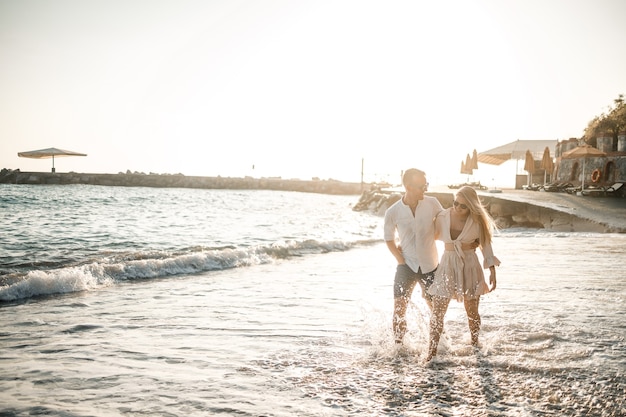 Ein verliebtes Paar geht am Strand am Meer spazieren. Junge Familie bei Sonnenuntergang am Mittelmeer. Sommerferienkonzept