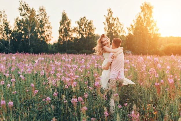 Ein verliebtes Paar geht durch eine Blumenwiese. Liebe und Frühling blühen. Ein Mann umarmt eine Frau