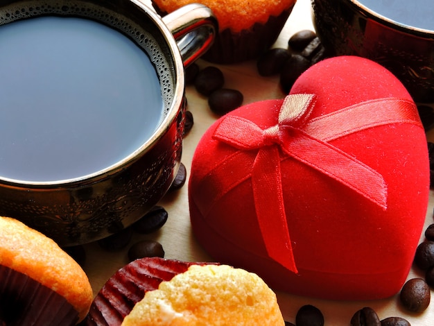 Ein Verlobungsring in einem roten Etui, zwei Tassen Kaffee und ein Cupcake. Konzept Heiratsantrag. Frühstück zum Valentinstag.