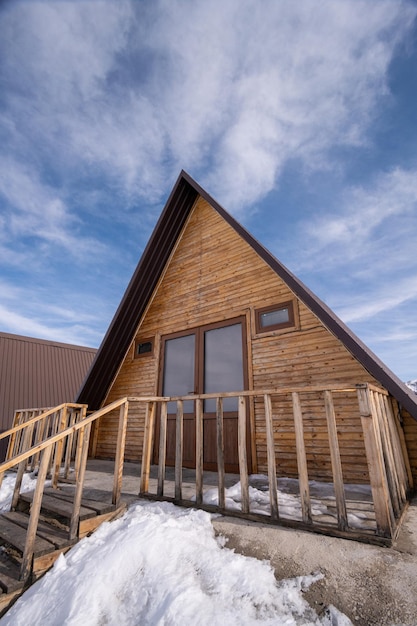 Ein vertikaler Schuss von einem Holzhaus, umgeben von Schnee Ein Erholungsgebiet in den Bergen