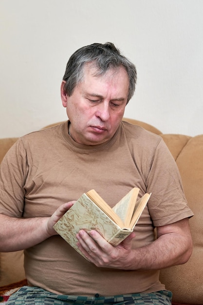 Ein volljähriger Mann sitzt auf dem Devani und liest ein Buch